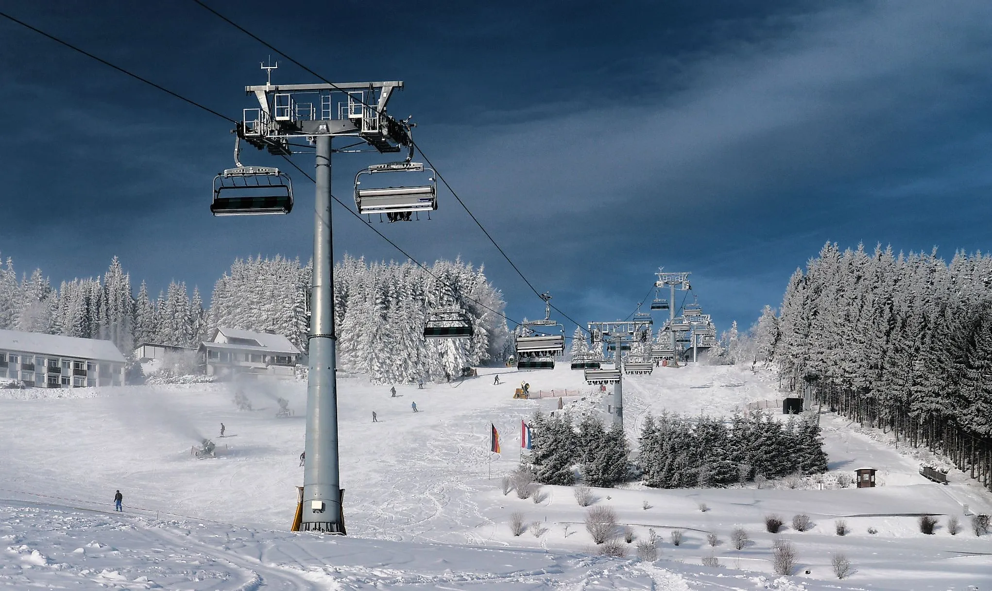 Blick auf die Skipiste am Ritzhagen in Willingen mit modernen Sesselliften und verschneiten Tannen.