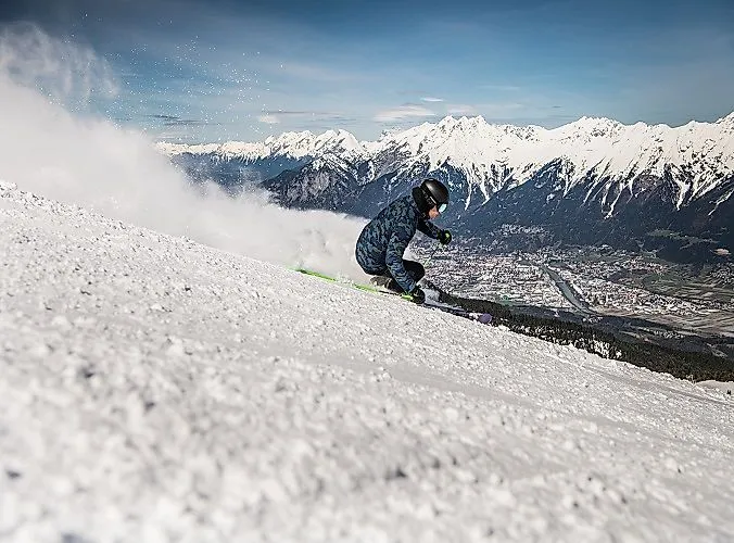 Esquiadores en acción con vistas al valle del Inn cubierto de nieve y a los Alpes en el Glungezer, en el Tirol.