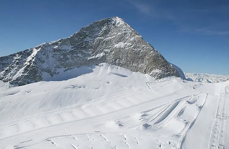 Schneebedeckter Hintertuxer Gletscher mit präparierten Pisten vor der markanten Silhouette des Olperer-Gipfels.
