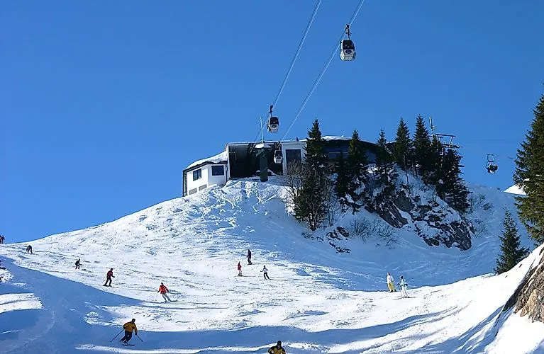 Skifahrer am Brauneck in Lenggries bei Sonnenschein – Gondelbahn über der verschneiten Piste