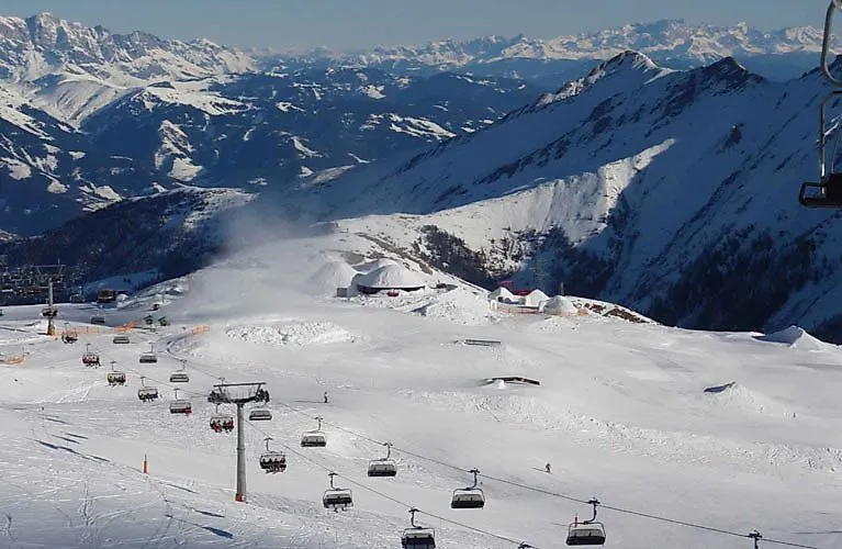 Verschneites Skigebiet am Kitzsteinhorn mit Sesselliften und Wintersportlern vor alpiner Bergkulisse.