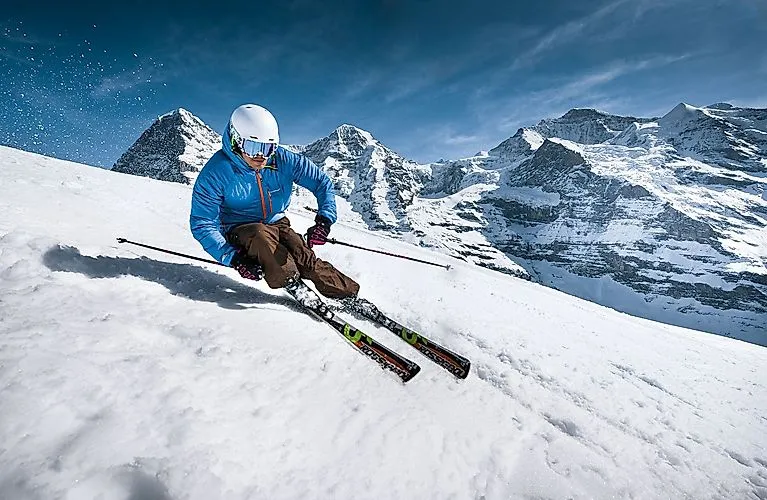Skifahrer in Action vor verschneiten Gipfeln der Jungfrau Region mit Blick auf die Eiger-Nordwand.