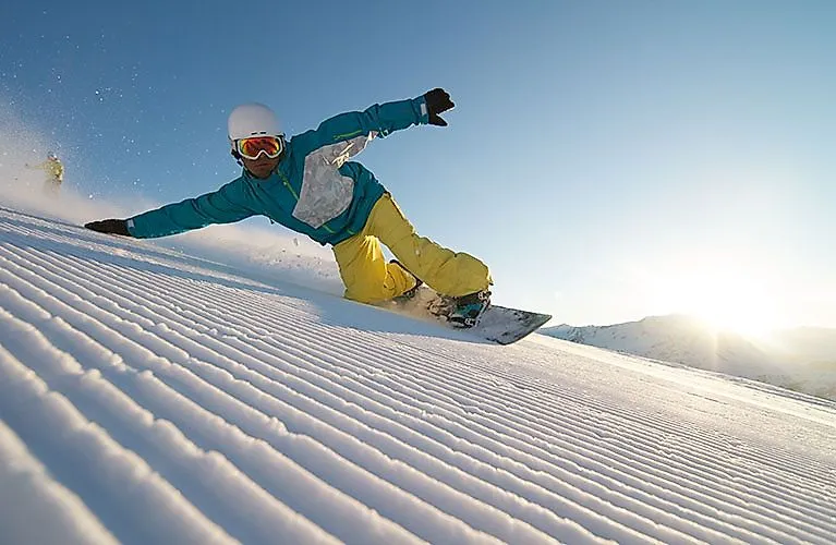 Snowboarder gleitet bei Sonnenschein über frisch präparierte Skipiste in Nauders.