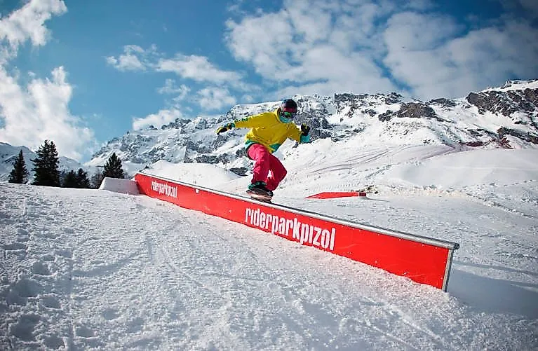 Snowboarder beim Trick im Riderpark Pizol vor verschneiter Bergkulisse.