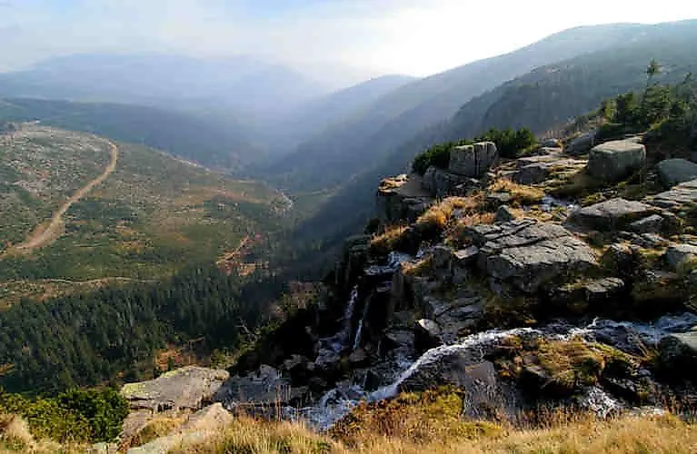 Weitblick über das grüne Riesengebirge bei Spindlermühle mit Felsen, Tälern und einem kleinen Wasserfall im Vordergrund