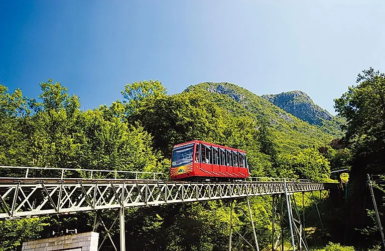Zahnradbahn fährt durch grüne Wälder am Monte San Salvatore in der Schweiz