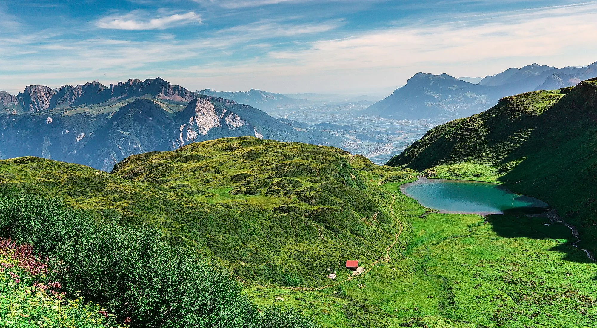 Panorama vom Pizol mit Bergsee und grünen Hügeln vor den Alpen bei St. Gallen