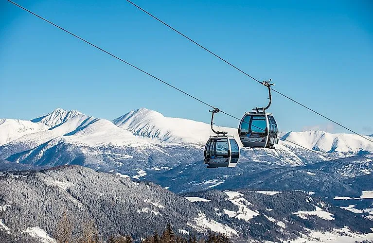 Zwei moderne Gondeln schweben über das verschneite Skigebiet Katschberg mit winterlicher Alpenkulisse.