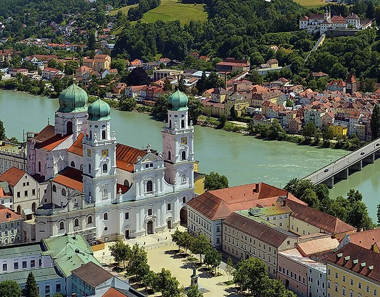 Barocker Stephansdom in Passau mit grünen Zwiebeltürmen am Donauufer, umgeben von Altstadt und grüner Hügellandschaft