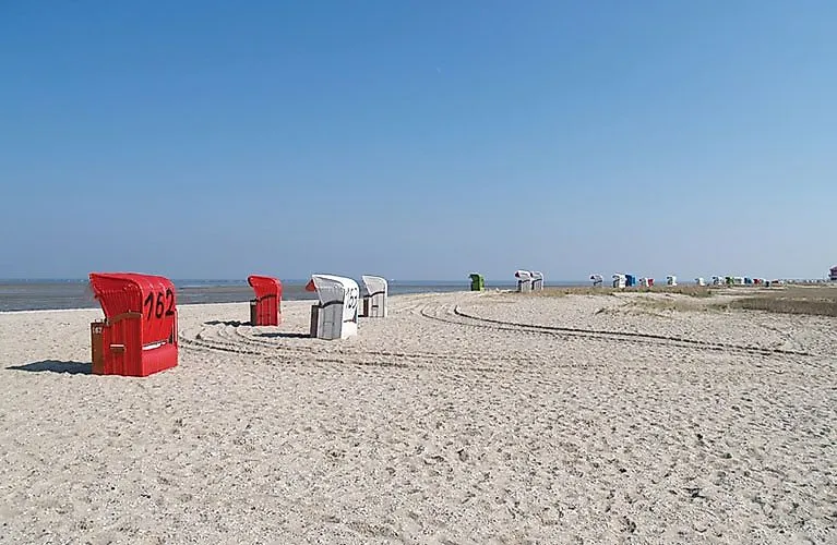 Weiter Sandstrand an der Nordseeküste in Hooksiel mit roten und weißen Strandkörben an einem sonnigen Tag