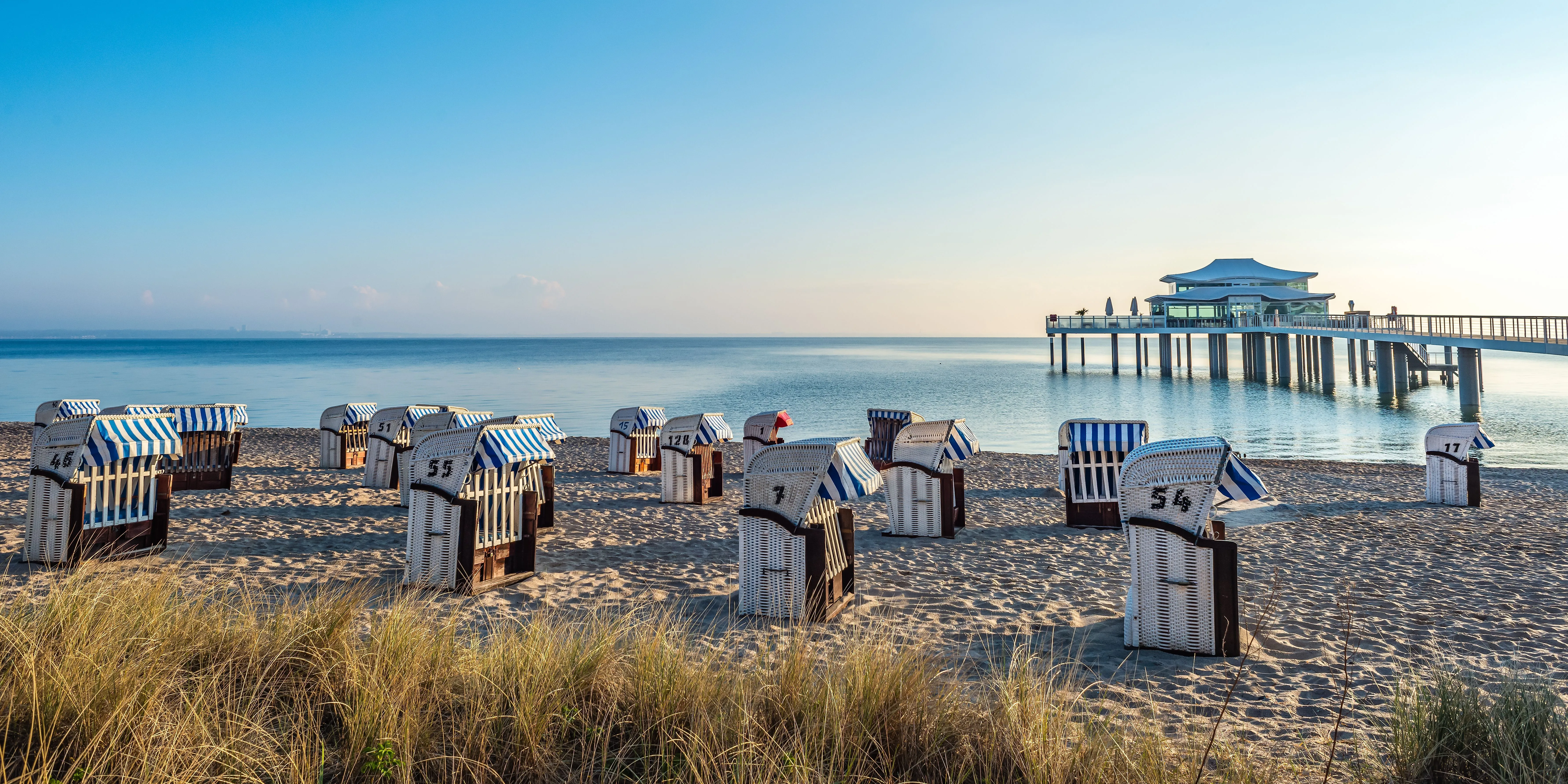 Strandkörbe am Timmendorfer Strand mit Blick auf die Seebrücke und ruhige Ostsee.