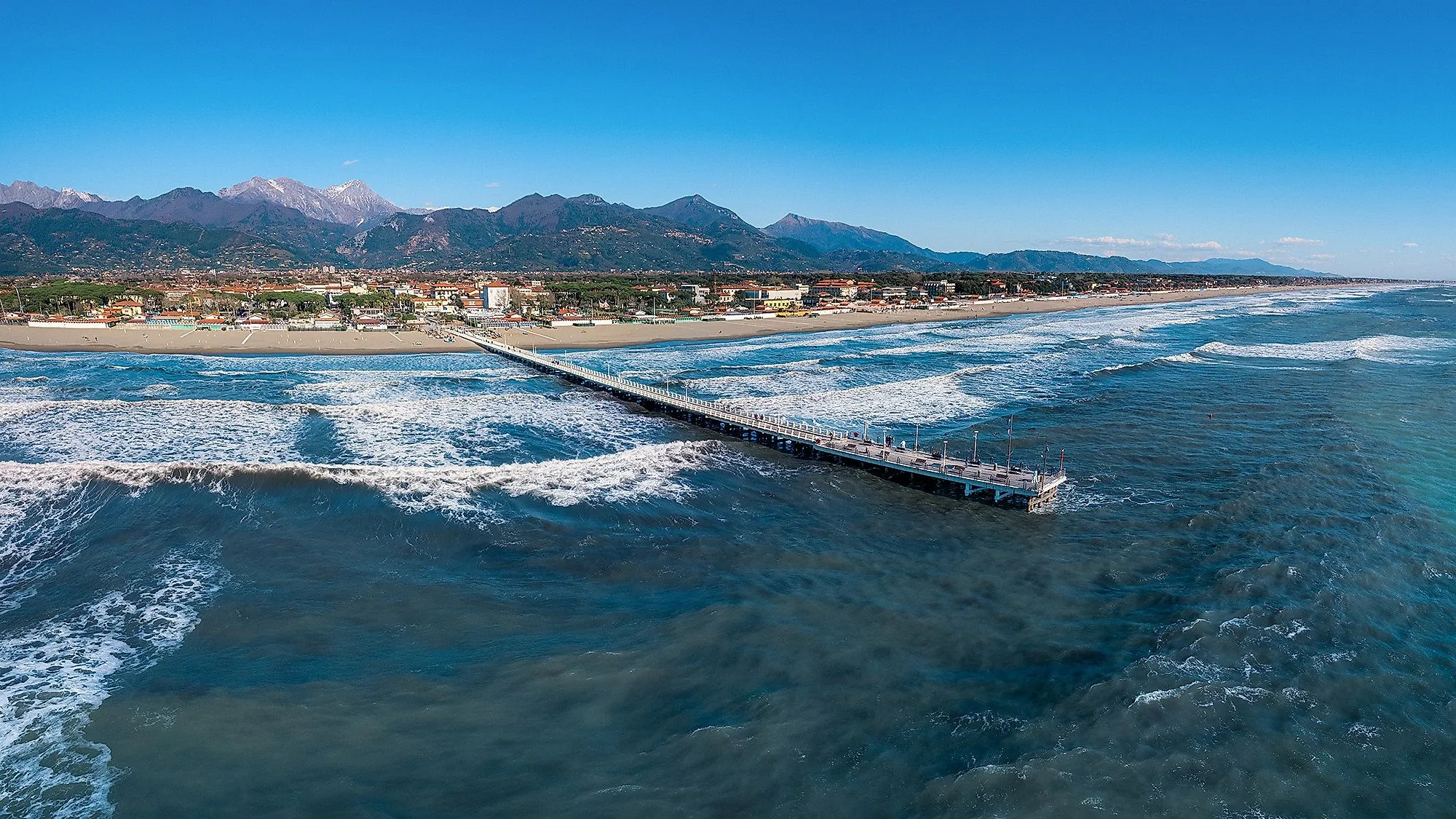 Strand und Promenade von Forte dei Marmi in der Toskana mit Blick auf das Meer und die Apuanischen Alpen im Hintergrund.