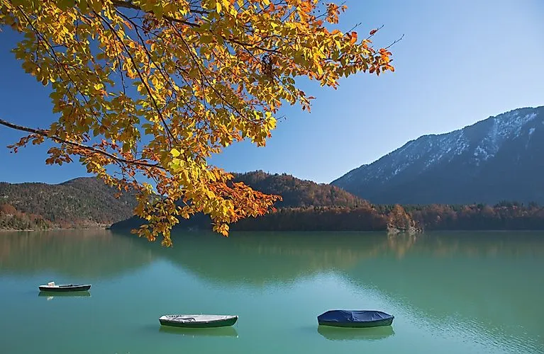Boote am Sylvensteinsee nahe Lenggries – herbstliche Farben und Bergkulisse spiegeln sich im Wasser