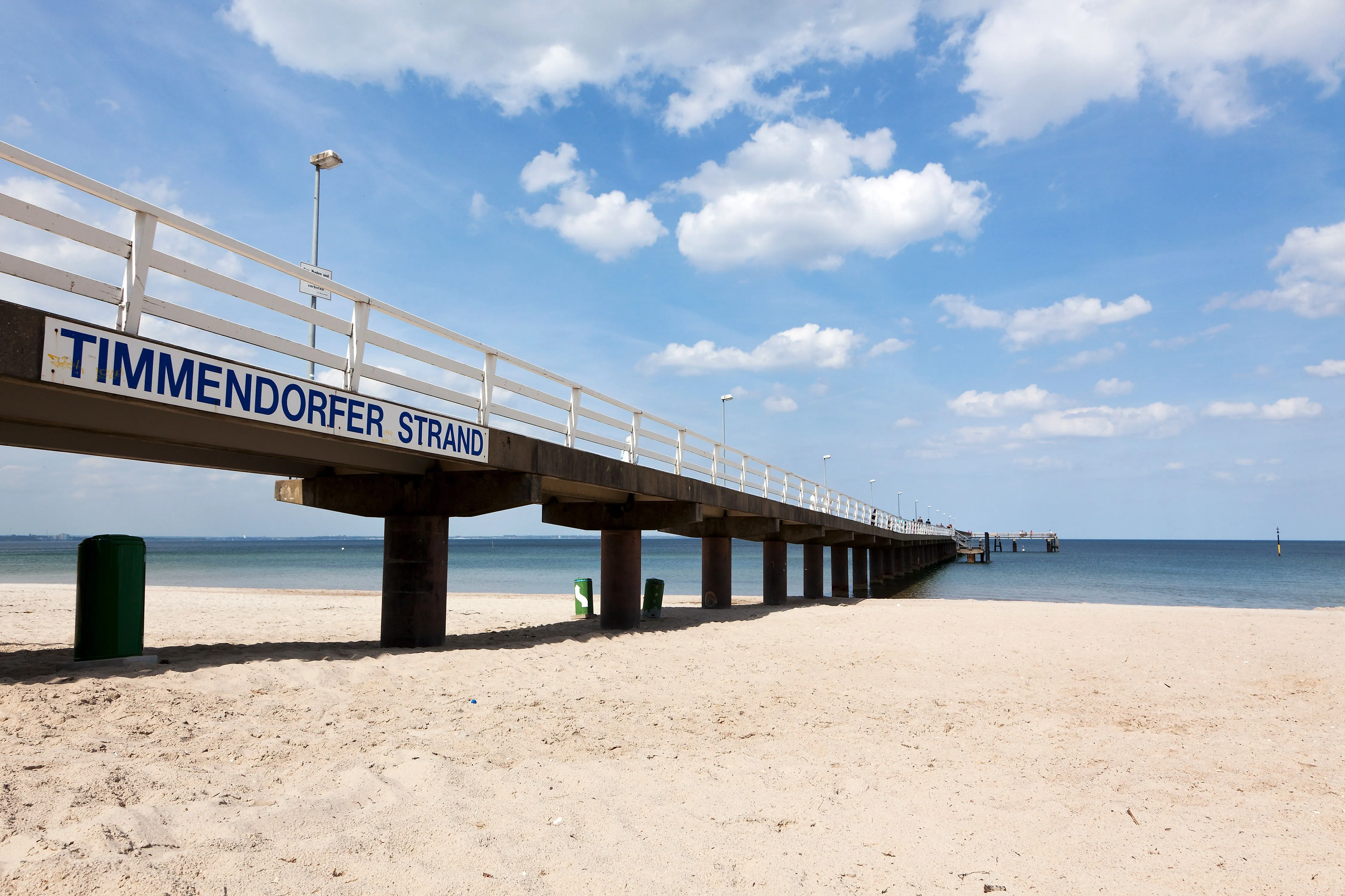 Seebrücke Timmendorfer Strand vor blauem Himmel und ruhiger Ostsee an einem sonnigen Tag.