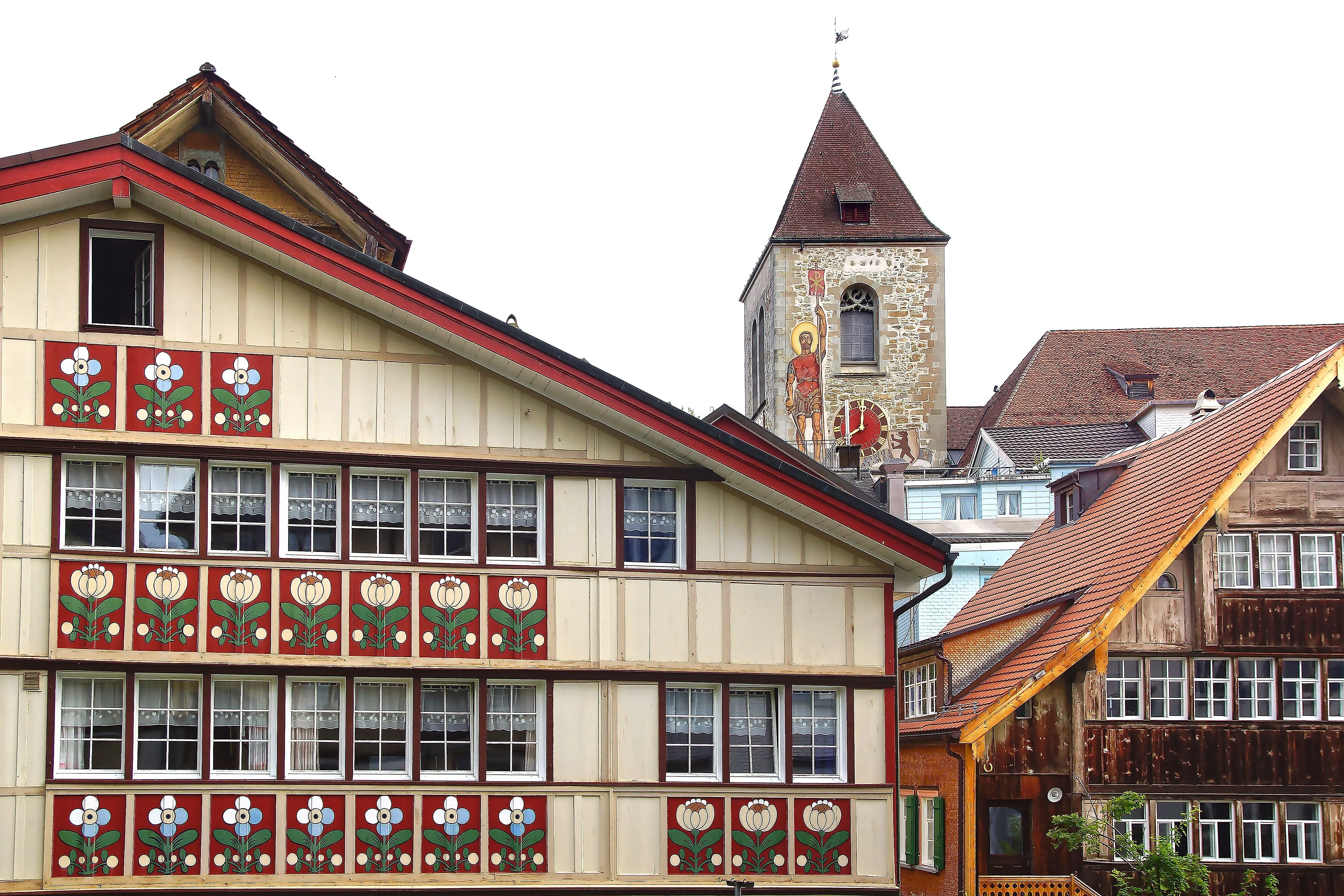 Traditionelle bemalte Häuserfassade in Appenzell mit Kirchturm im Hintergrund