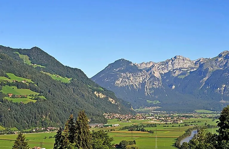 Blick ins grüne Tal von Uderns im Zillertal an einem sonnigen Sommertag mit Bergen im Hintergrund.