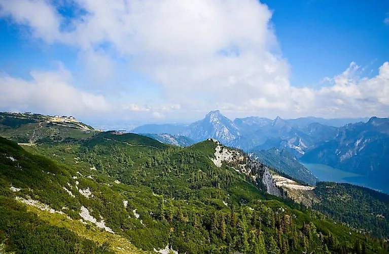 Weitblick über grüne Berghänge und den Traunstein vom Feuerkogel bei Ebensee an einem Sommertag.