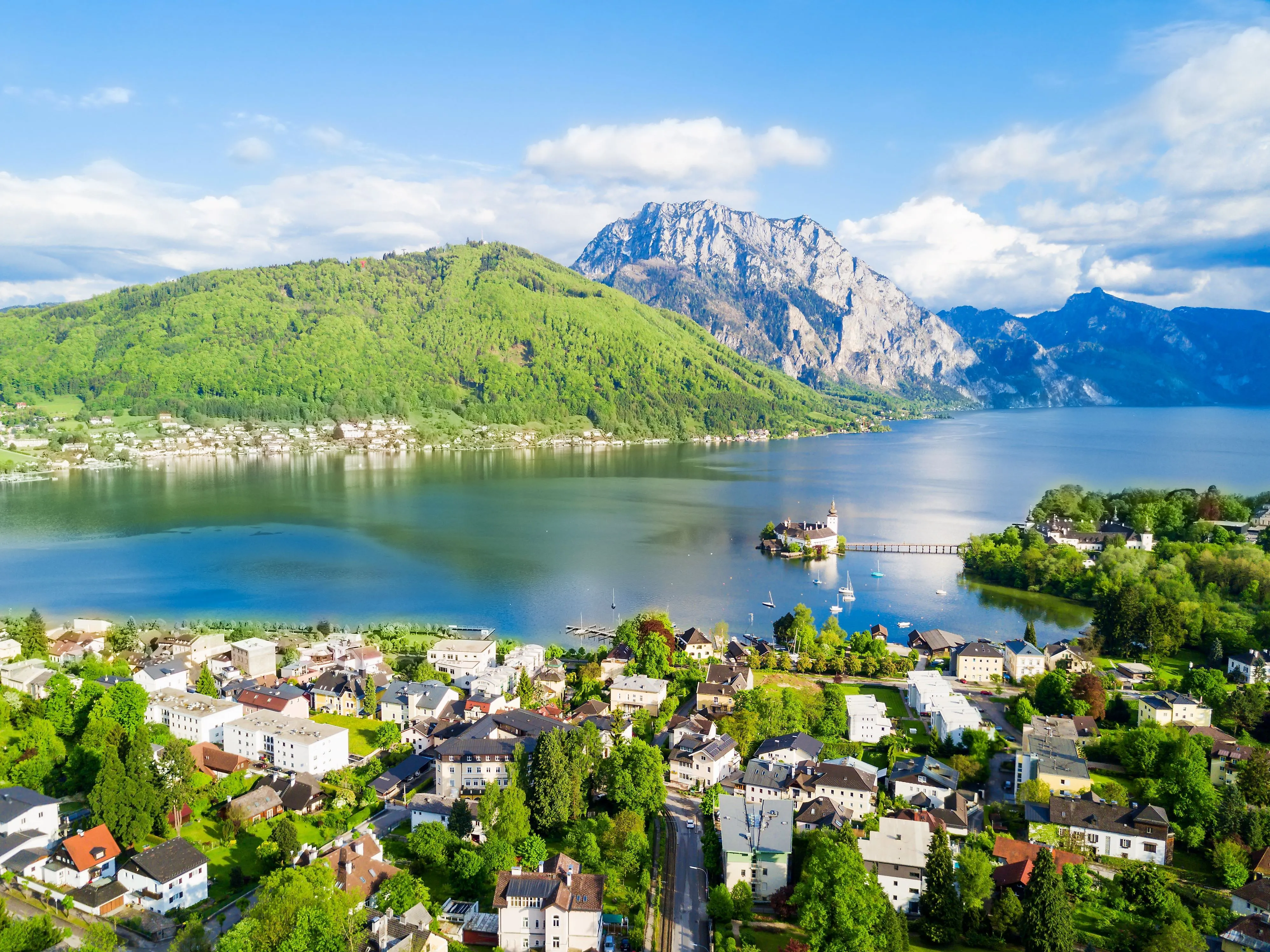 Luftaufnahme von Gmunden mit Traunsee, Schloss Ort und Bergkulisse im Frühling.