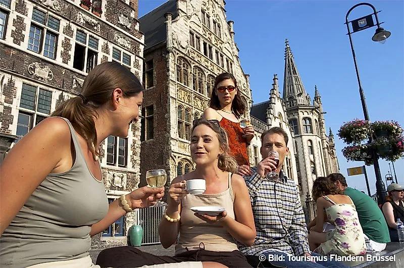 Menschen genießen Getränke vor historischen Gebäuden in Gent, Belgien