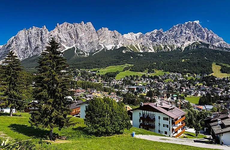 Panoramatický výhled na Cortinu d'Ampezzo s tradičními domy a pozoruhodným pohořím Dolomity