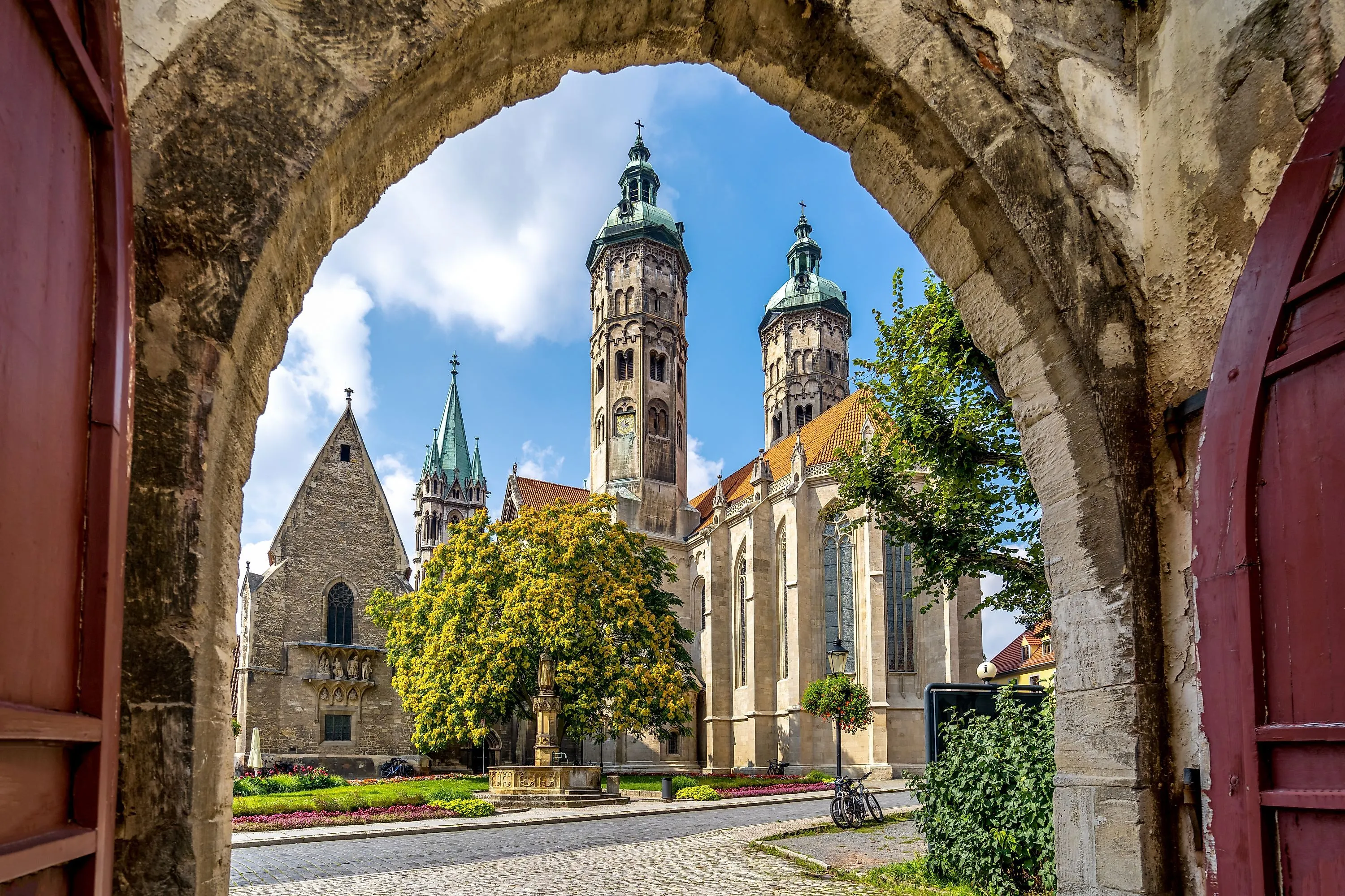 Naumburger Dom in Sachsen-Anhalt mit Türmen und Garten, gesehen durch ein Tor