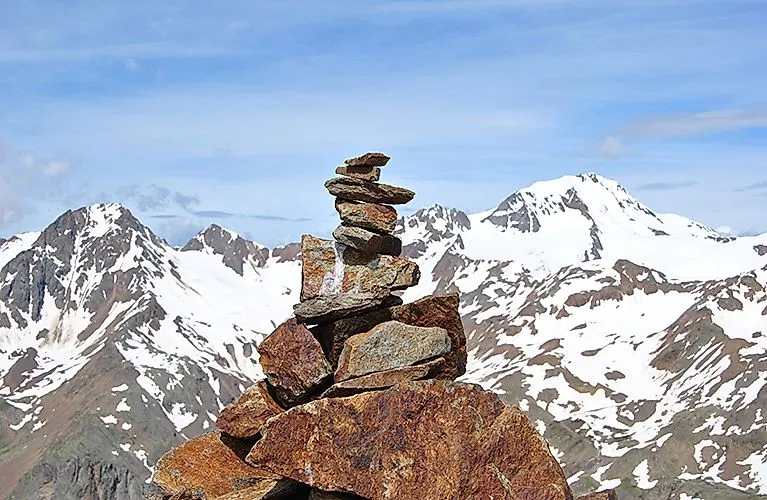 Steinmännchen vor der Kulisse schneebedeckter Gipfel im Schnalstal.