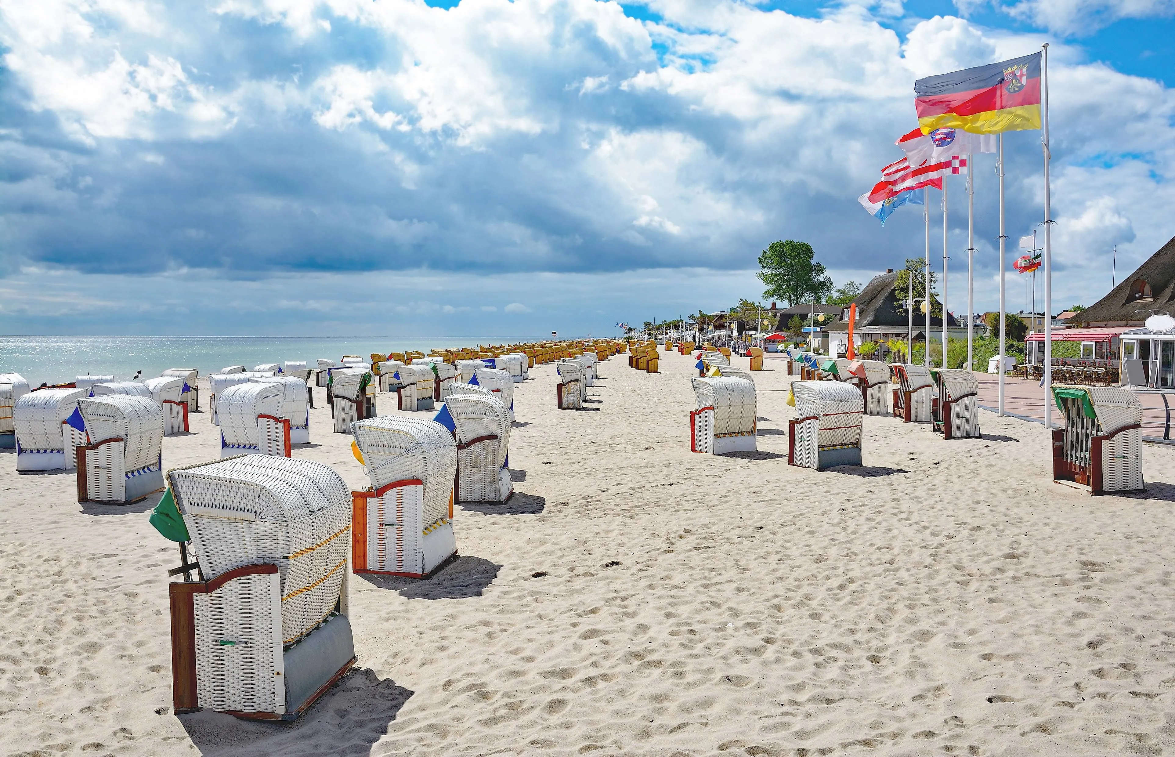 Strandkörbe am breiten Sandstrand von Dahme an der Ostsee mit Promenade und Flaggen