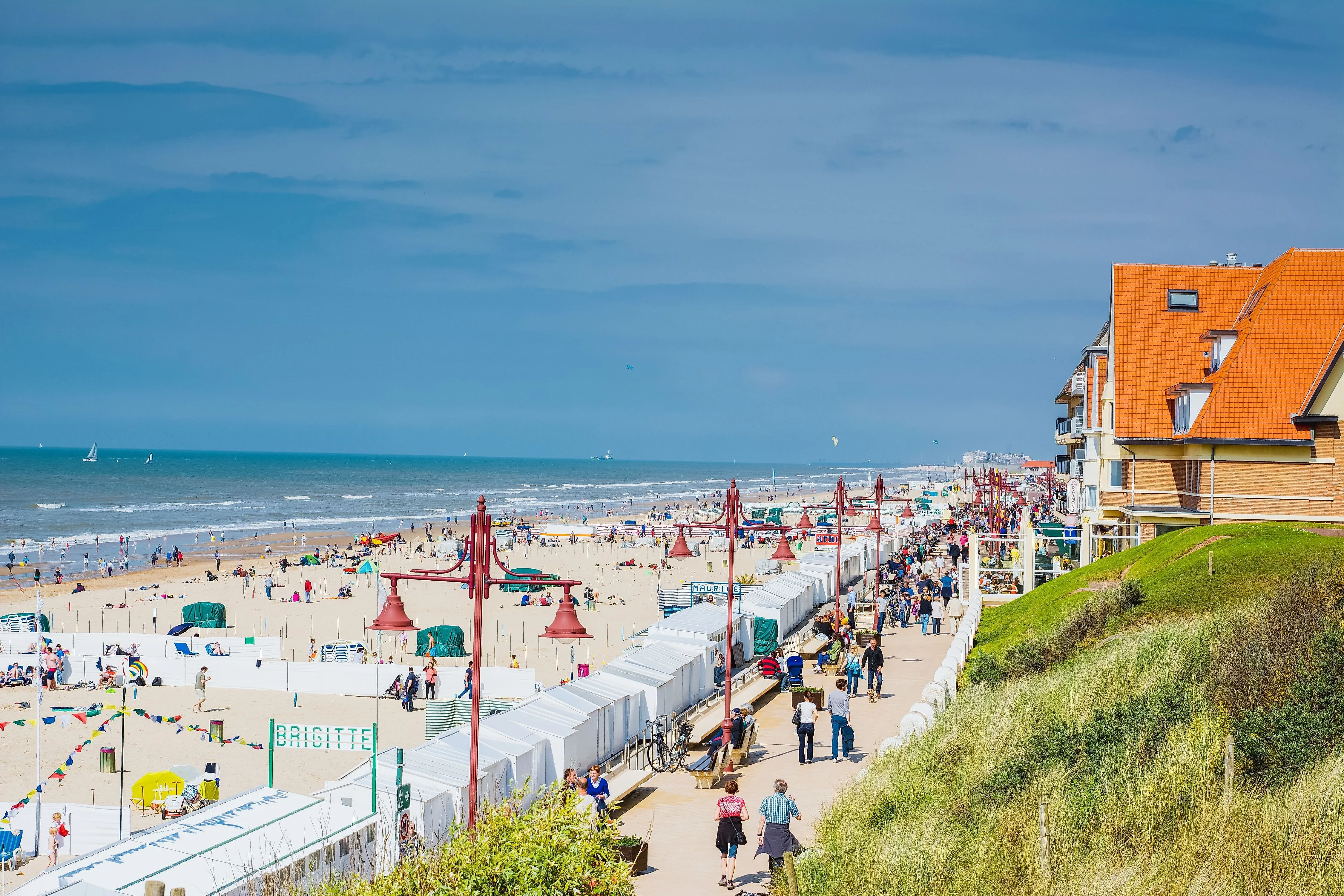 Strandpromenade von De Haan an der belgischen Küste mit vielen Besuchern und Strandzelten