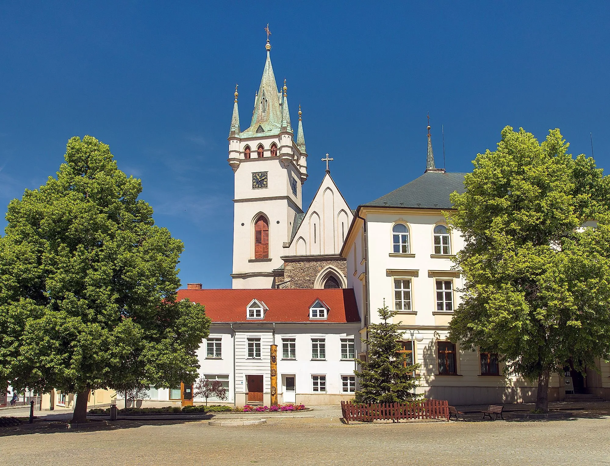 Stadtplatz von Humpolec mit der Kirche St. Nikolaus und historischen Gebäuden im Sommer.