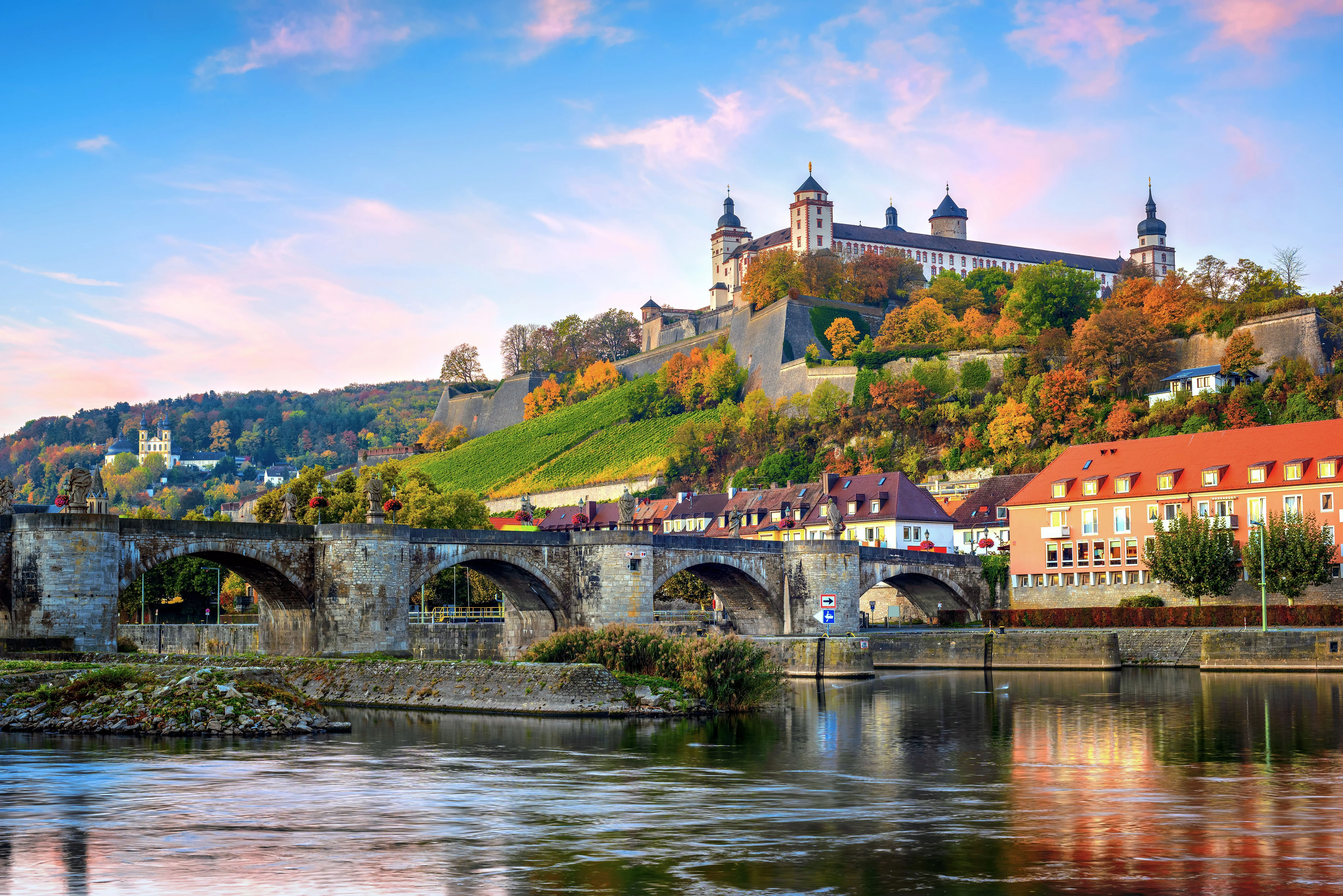 Die Festung Marienberg thront über dem Main und der alten Mainbrücke in Würzburg im herbstlichen Abendlicht.