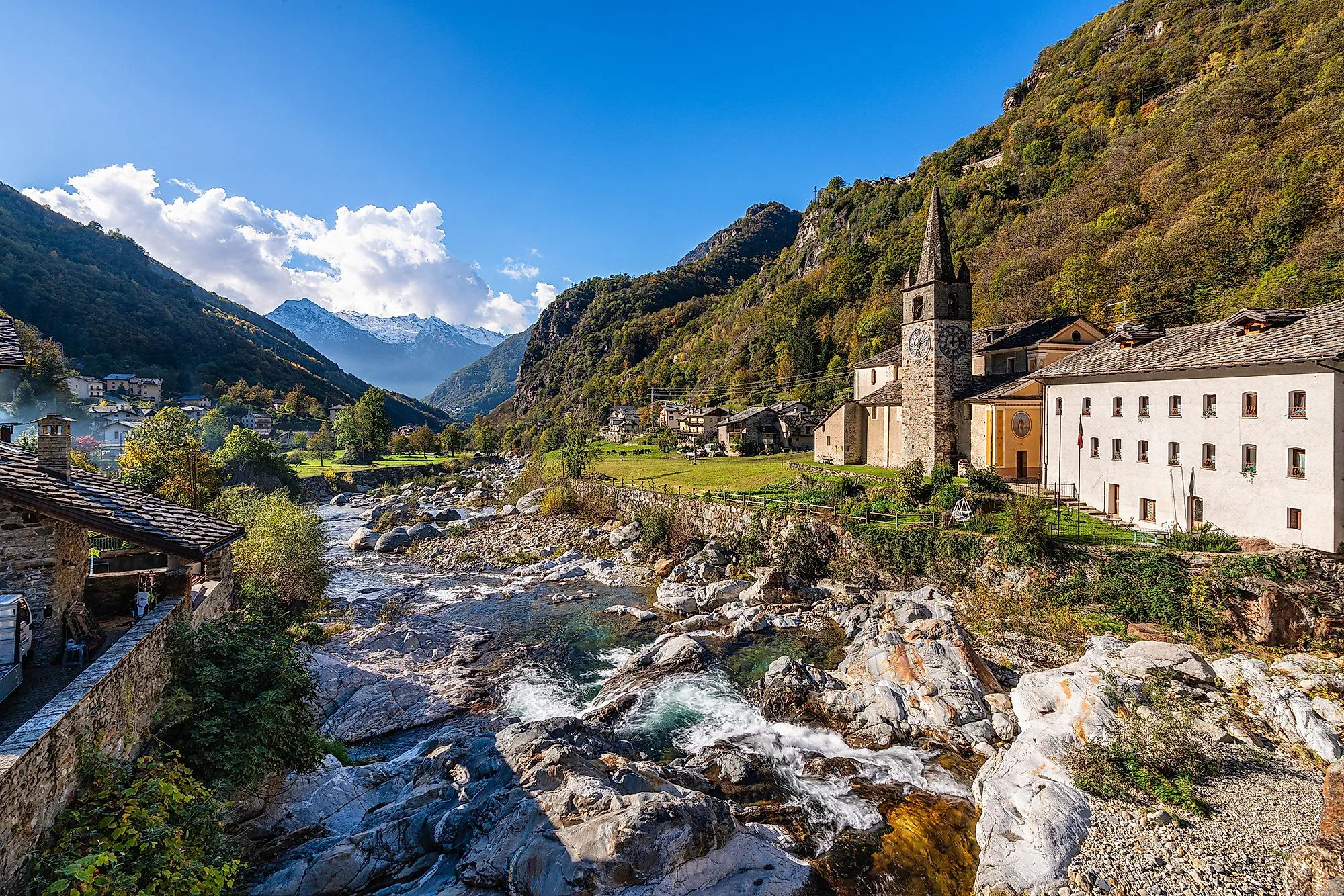 Bergdorf mit Kirche im Lys-Tal, grüner Talgrund und schneebedeckte Berge