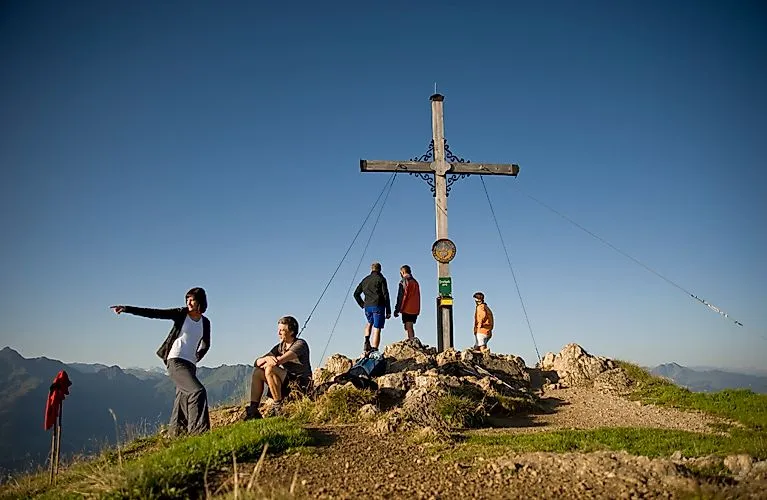 Wandergruppe am Gipfelkreuz mit Weitblick über die Berge in der Wildschönau