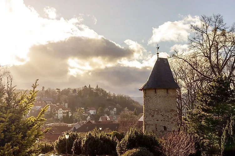 Blick auf Wernigerode mit historischem Turm und Häusern mit dramatischen Sonnenstrahlen, die durch die Wolken scheinen.
