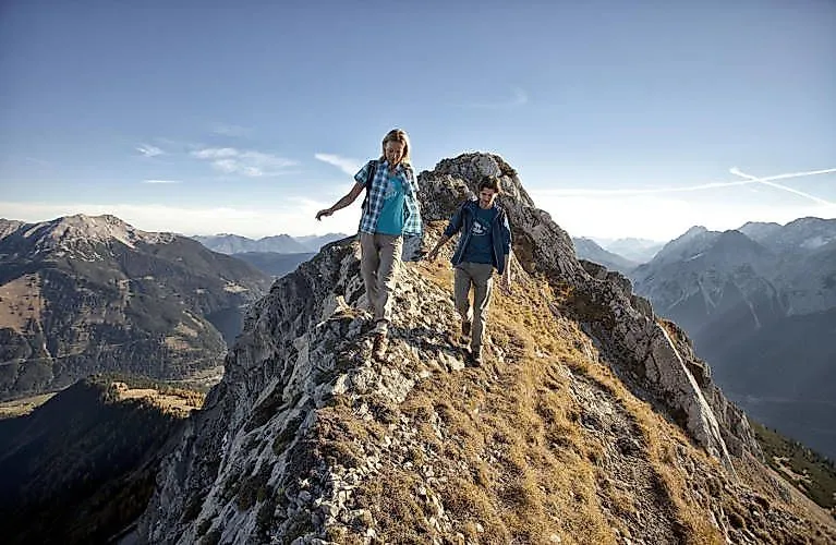 Zwei Wanderer auf einem Grat in der Tiroler Zugspitz Arena bei Lermoos, mit beeindruckendem Panoramablick auf die Alpen.