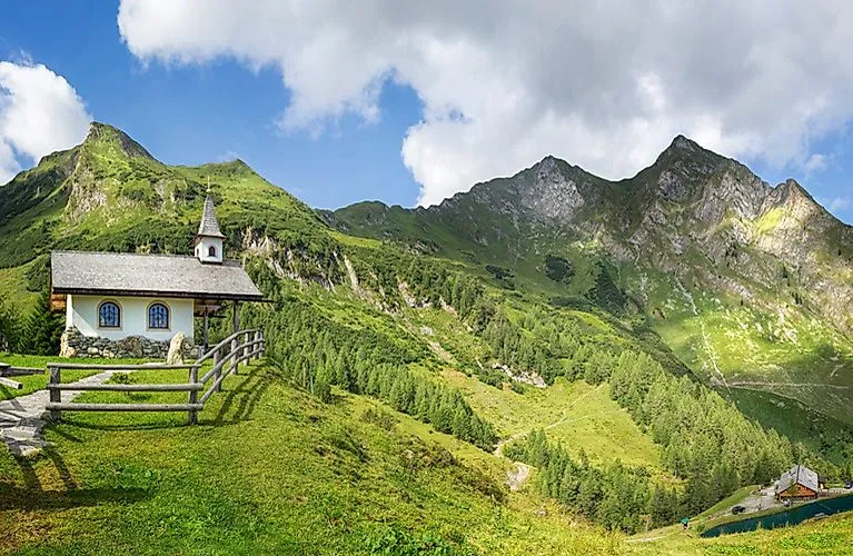 Kapelle in Bad Gastein vor grüner Alpenkulisse unter blauem Himmel