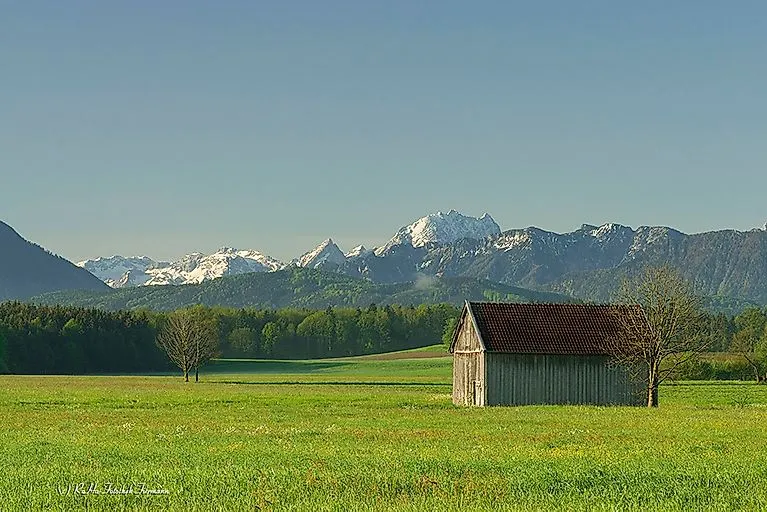 Sommerliches Alpenpanorama bei Anger mit grüner Wiese, Hütte und Bergkette