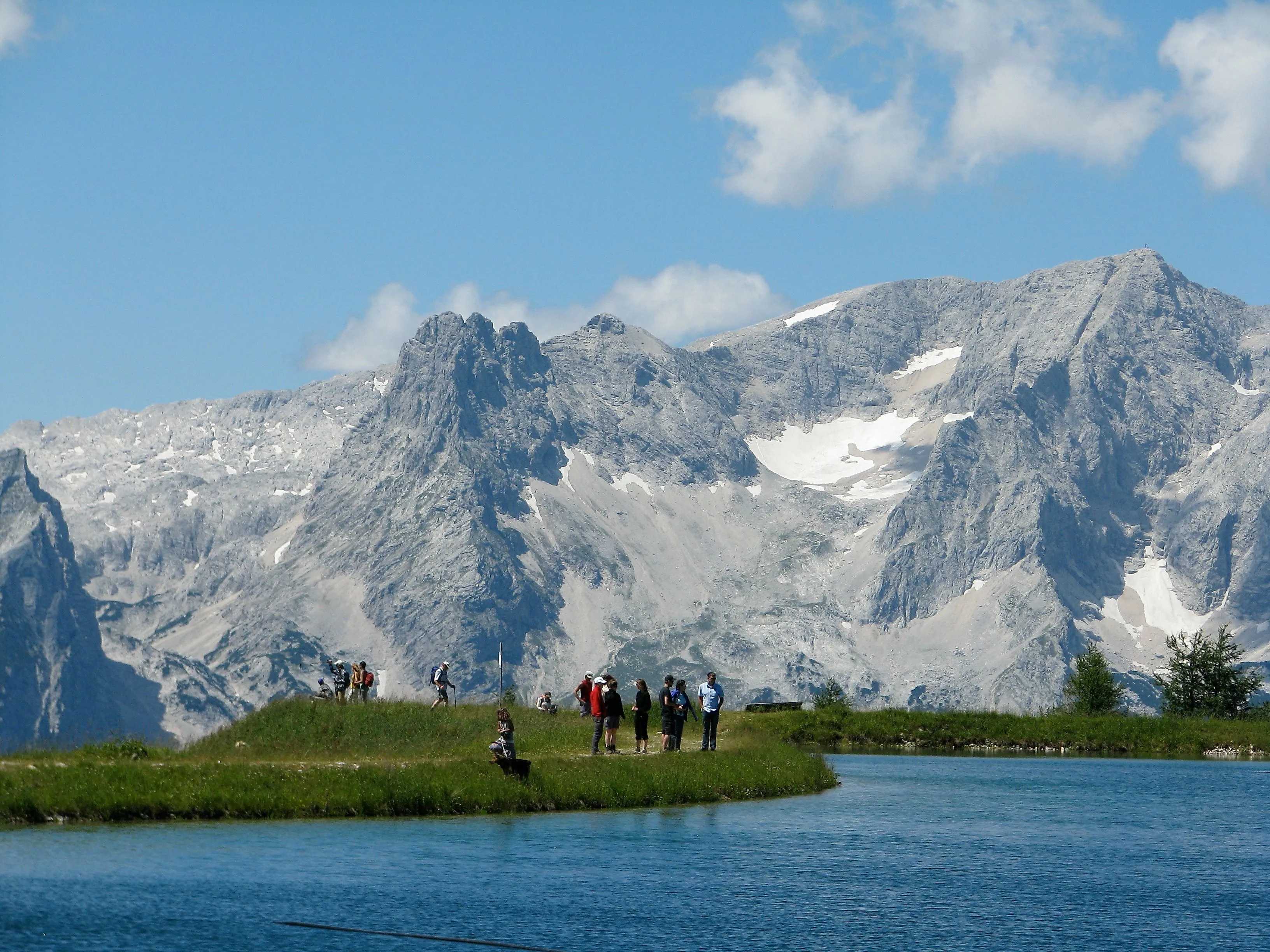 Wanderer vor beeindruckender Bergkulisse am Ufer eines idyllischen Bergsees in Hinterstoder bei klarem Sommerwetter.