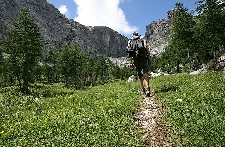 Wanderer auf einem alpinen Pfad in Kärnten mit Blick auf Felsen und Wälder
