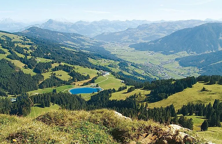 Ďaleký výhľad na zelené hory a alpské pastviny pri Westendorfe v lete