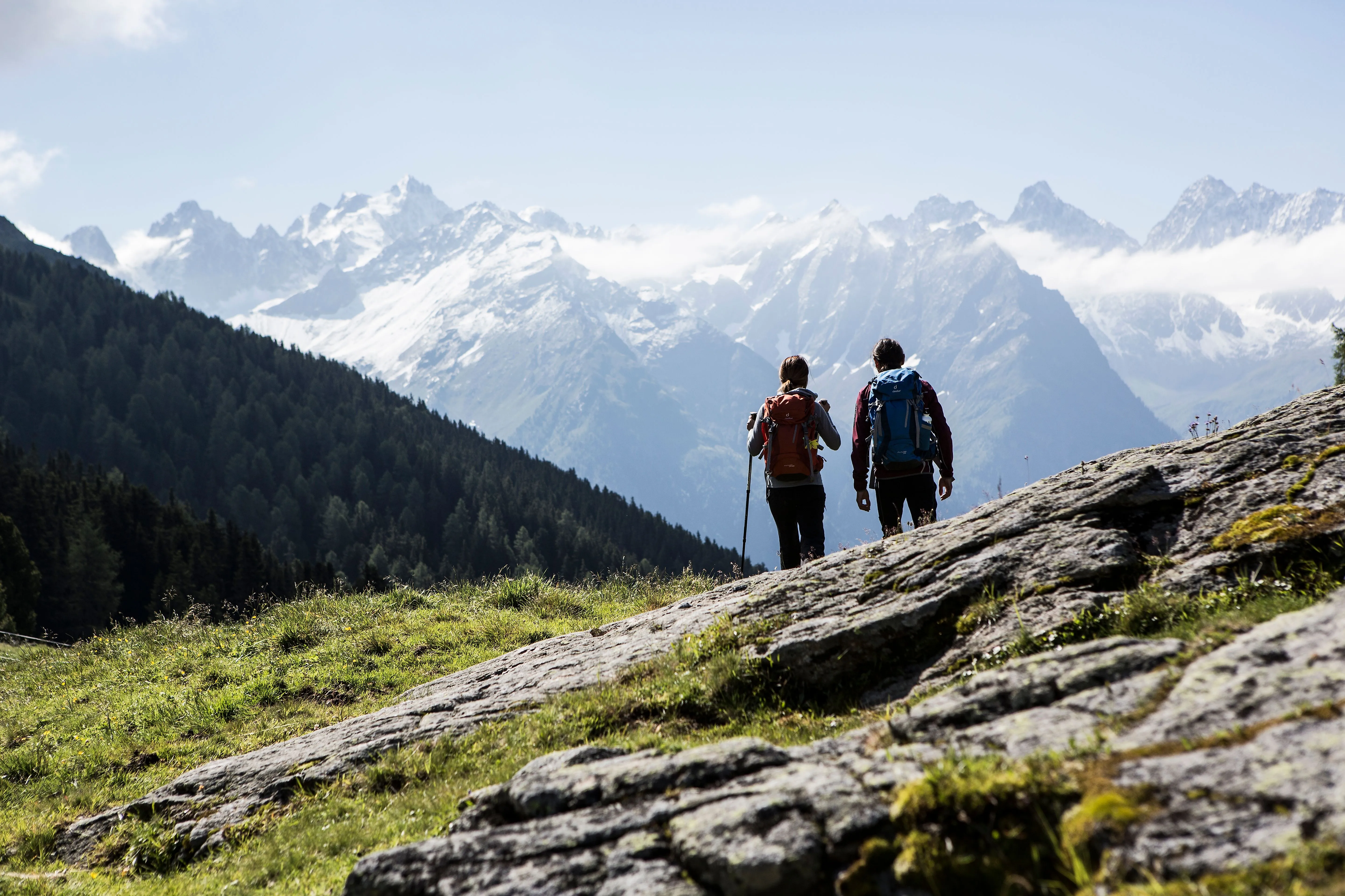 Two hikers on an alpine meadow with a view of snow-covered mountain peaks in the Kaunertal.
