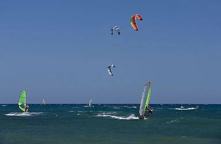 Surfer und Kitesurfer auf dem Meer vor Cambrils bei starkem Wind – beliebter Spot für Wassersport an der Costa Daurada