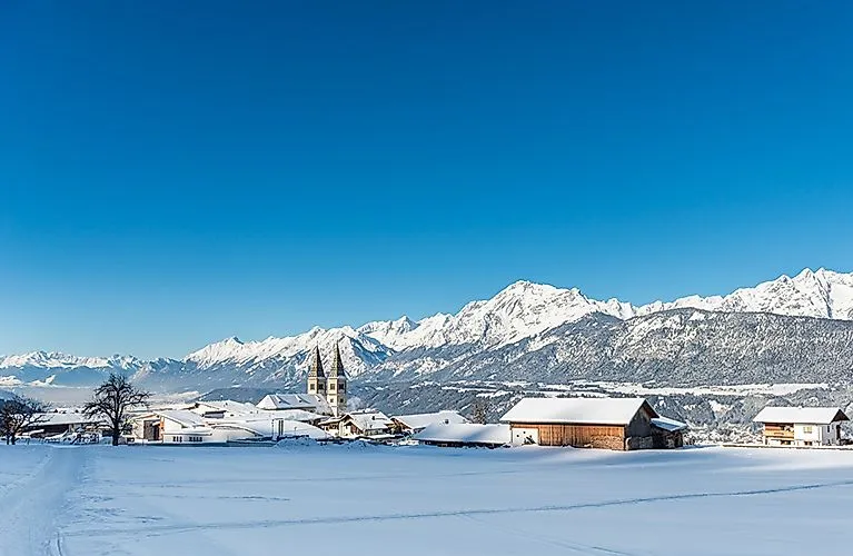 Verschneite Landschaft mit Blick auf Weerberg, seine Kirchtürme und das Karwendelgebirge.