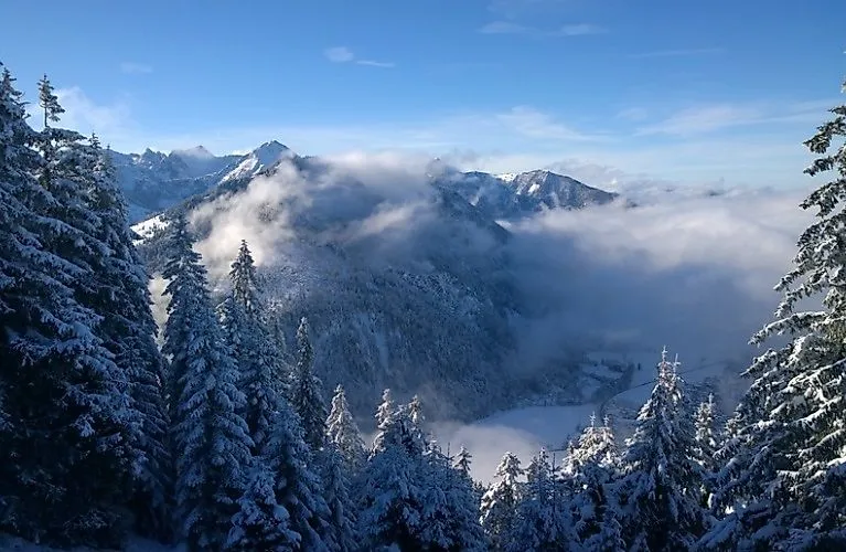 Verschneite Winterlandschaft in Bayrischzell mit Blick auf die Alpen und Tal im Nebel