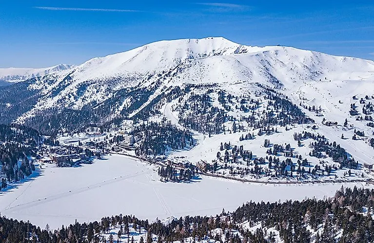 chneebedeckter Turracher See mit Blick auf das Skigebiet und die umliegenden Berge