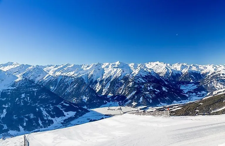 Panoramablick auf das schneebedeckte Hollersbachtal mit imposanter Bergkulisse unter strahlend blauem Winterhimmel.