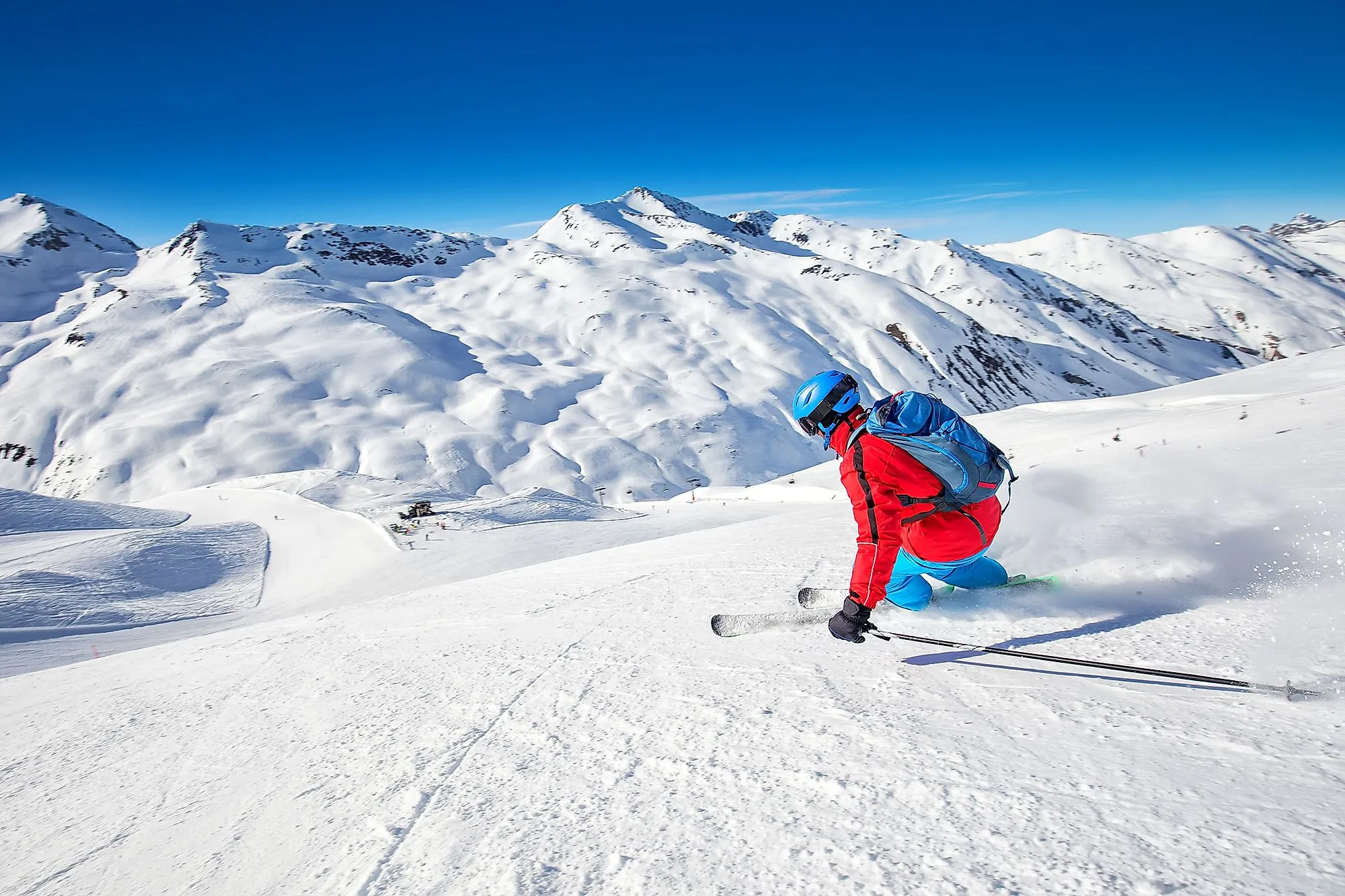 Skifahrer in Livigno fährt eine weiße Piste hinunter vor hochalpiner Kulisse