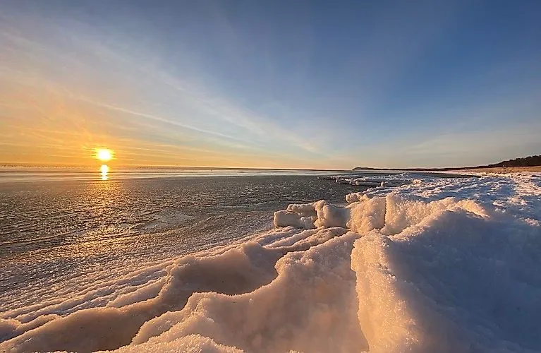 Winterliche Landschaft auf Mönchgut mit schneebedecktem Ufer und Blick auf das zugefrorene Meer.