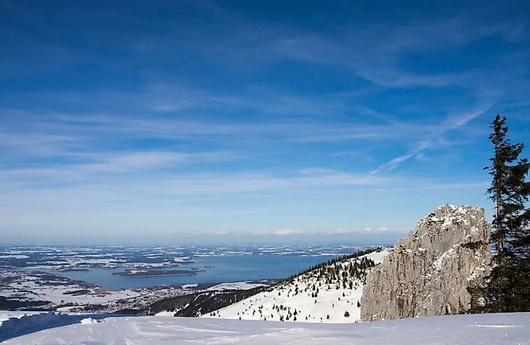 Winterliche Aussicht vom Gipfel auf den Chiemsee und die verschneite Voralpenlandschaft bei klarem Himmel