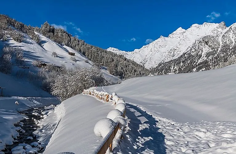 Besneeuwd winterpad in Gossensass met uitzicht op de besneeuwde Alpen.