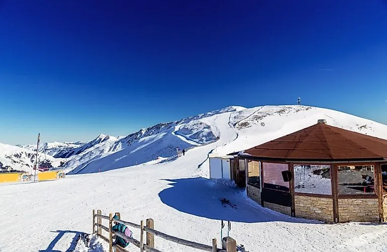 Bergstation mit Rundhütte und verschneiten Pisten im Skigebiet Hollersbach an einem strahlenden Wintertag.